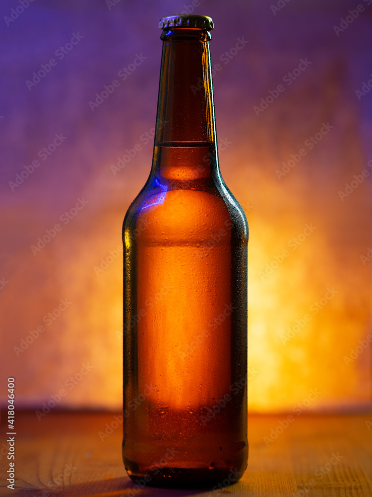 A bottle of cold beer in water drops on a yellow background with neon lighting A bottle of cold beer in water drops on a yellow background with neon lighting