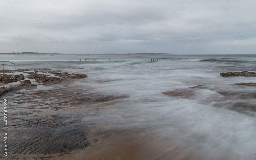 Wave water flowing between rocks on the coastline.