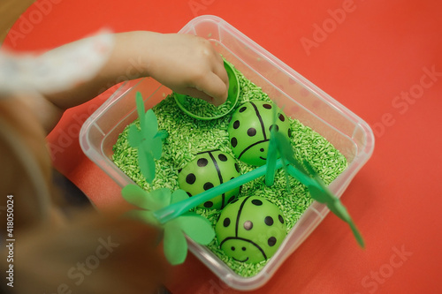 Toddler playing with colorful rice in the sensory box. Baby's sensory educational kit.