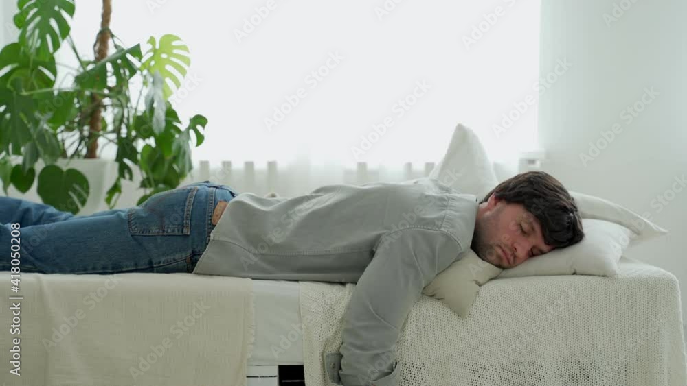 Exhausted young man falling asleep on bed, feeling no energy after hard working day. Businessman flopping down on bed, needs rest at home. Exhausted young man falling asleep on bed, feeling no energy after hard working day. Businessman flopping down on bed, needs rest at home.