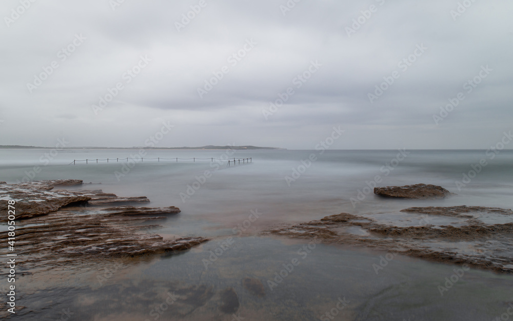 Fototapeta premium Rocky coastline and tidal pool view on a cloudy day.