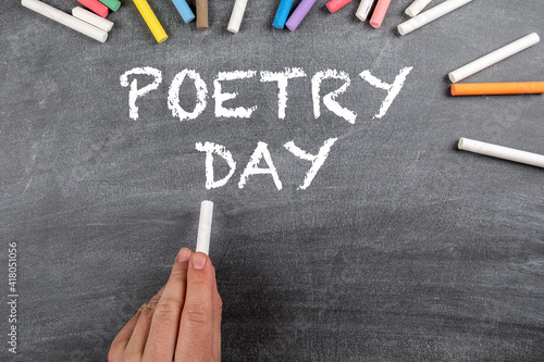 World Poetry Day 21 March. Dark chalkboard with colored chalk pieces