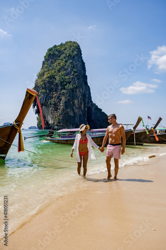 couple mid age on a tropical beach in Thailand, tourist on a white tropical beach, Railay beach with on the background longtail boat. Railay Beach in Krabi province. Ao Nang, Thailand. photo