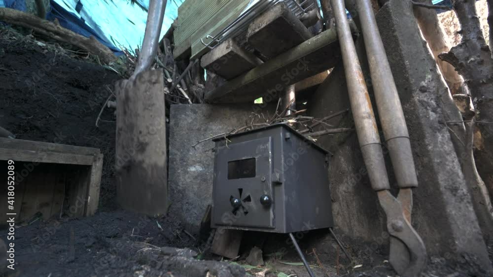 A spade digging around a log burning stove in an outdoor shelter A spade digging around a log burning stove in an outdoor shelter
