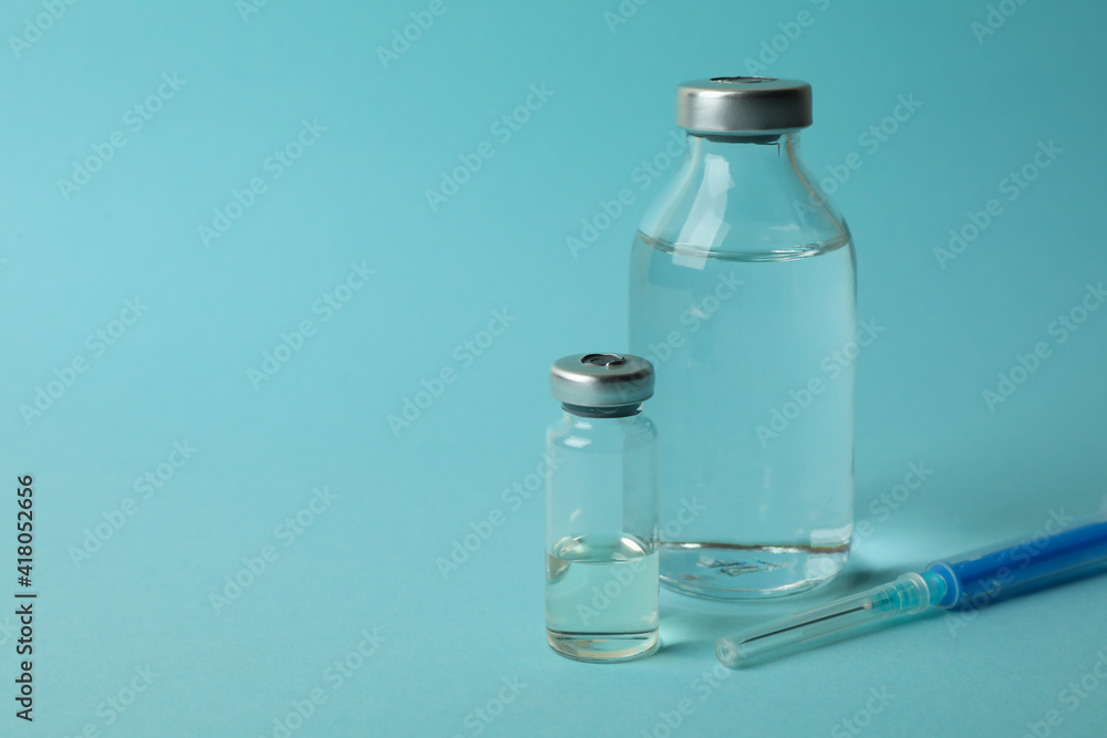 Vials with Covid - 19 vaccine and syringe on blue background Vials with Covid - 19 vaccine and syringe on blue background