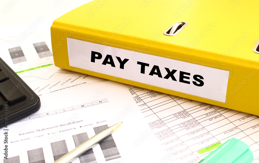 A yellow folder with documents labeled PAY TAXES lies on the office desk.