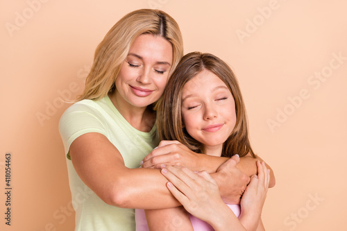 Photo of peaceful happy young woman and girl family hug dream care isolated on beige color background
