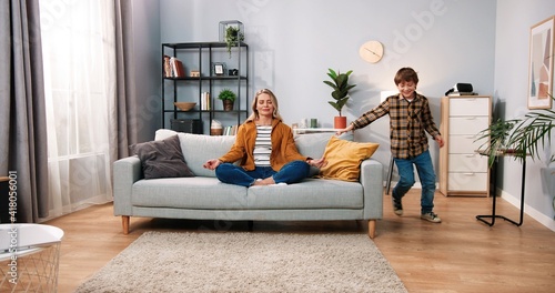 Tablou pe pânză Beautiful Caucasian mom parent sitting on couch meditating with calm face and cl