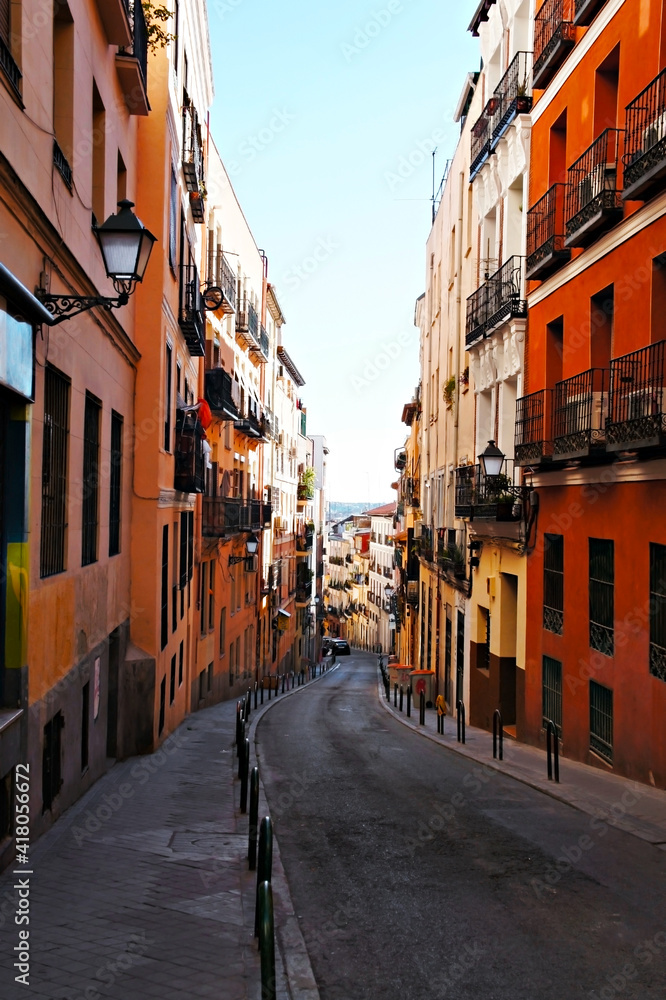 Narrow street between bright red and orange houses in Barcelona, travel walking, sidewalk, Spain