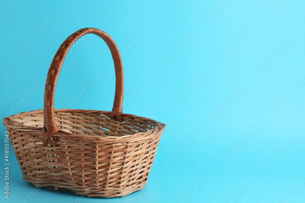 Empty wicker basket on light blue background, space for text. Easter item