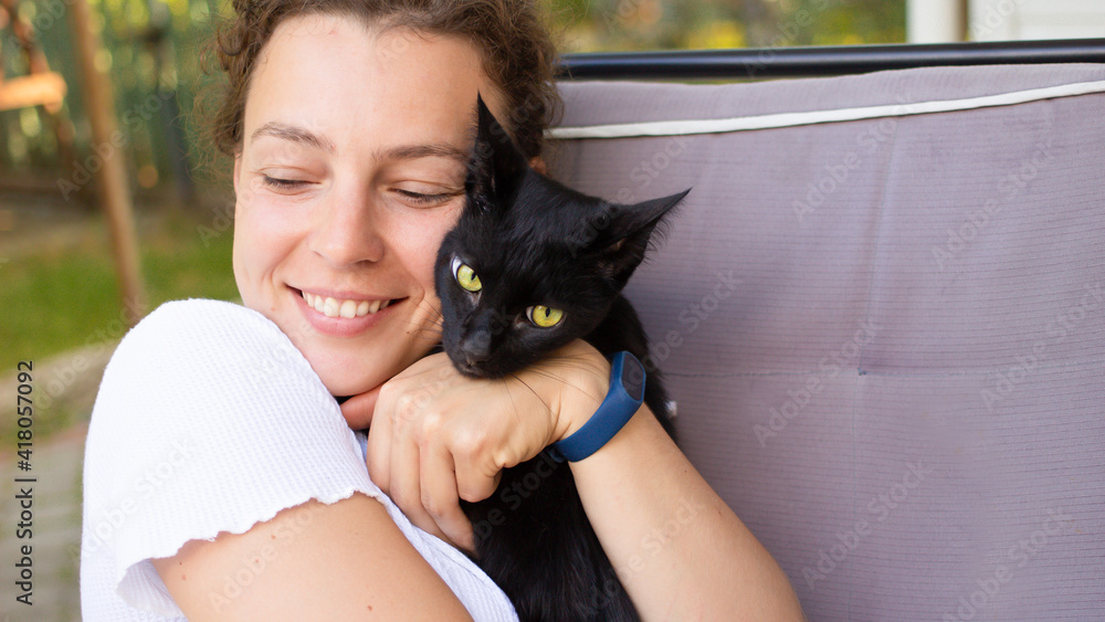 Beautiful young woman enjoying a cuddle with her black cat, hugging ...