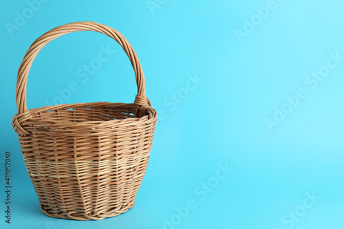 Empty wicker basket on light blue background  space for text. Easter item