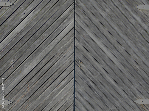 Texture of gray surface from boards. Large wooden gate. Light falls from the evening sun.