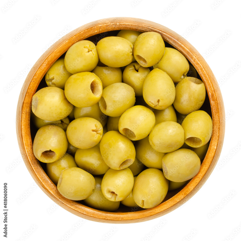 Pickled and pitted small green table olives in a wooden bowl. Green fruits of Olea europaea, unripe picked, cured and fermented before preservation. Closeup from above isolated over white food photo. Pickled and pitted small green table olives in a wooden bowl. Green fruits of Olea europaea, unripe picked, cured and fermented before preservation. Closeup from above isolated over white food photo.