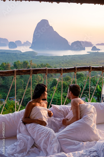 Phangnga Bay, couple waking up in bed in nature jungle looking out over ocean and jungle during sunrise at the wooden hut in the mountains of Thailand men and woman mid age morning sunrise Phanga photo