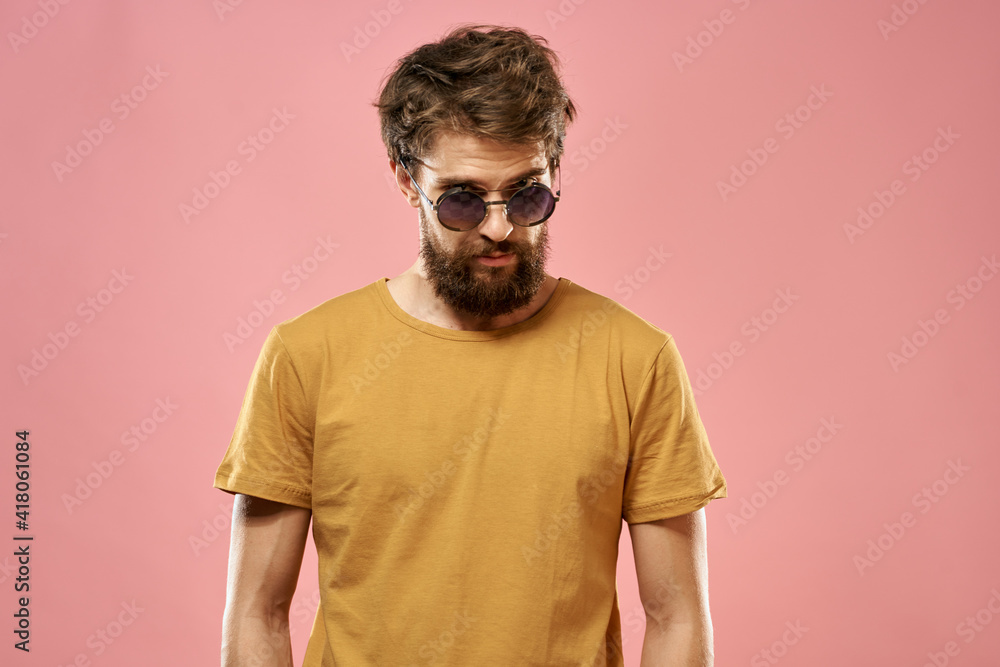 Cute bearded man in a yellow T-shirt dark glasses pink background Cute bearded man in a yellow T-shirt dark glasses pink background