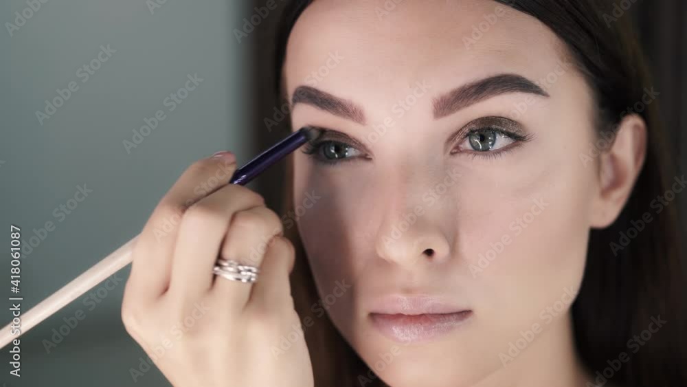 Woman make-up artist applies eye shadow and distributes it Woman make-up artist applies eye shadow and distributes it