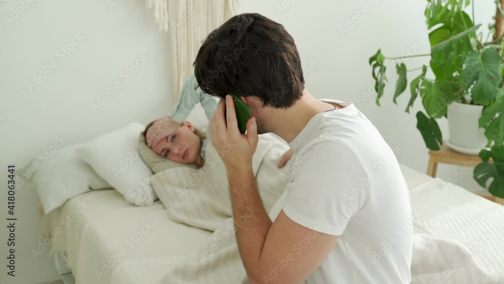 Worried husband calling doctor with sick wife lying on background. Husband consulting doctor on phone Worried husband calling doctor with sick wife lying on background. Husband consulting doctor on phone