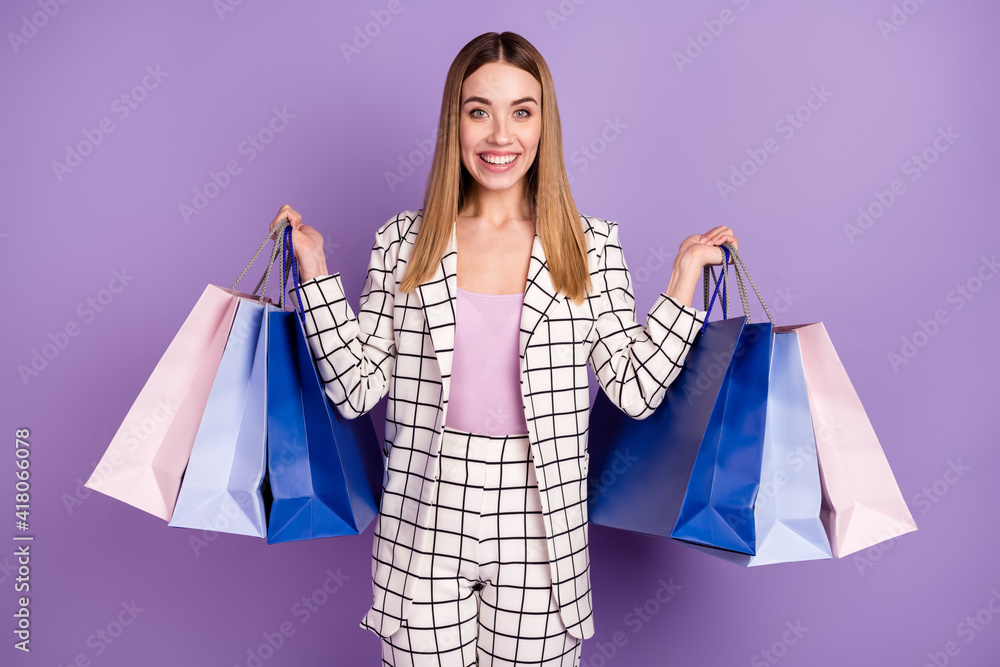 Photo of optimistic blond hair lady stand with bags wear suit isolated on violet color background Photo of optimistic blond hair lady stand with bags wear suit isolated on violet color background