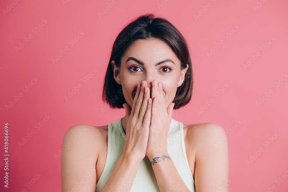 Woman on pink background covering mouth with hands looking at camera, funny excited with unexpected positive surprise Woman on pink background covering mouth with hands looking at camera, funny excited with unexpected positive surprise
