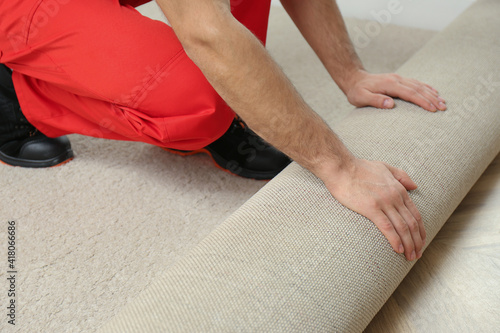 Worker rolling out new carpet flooring indoors, closeup