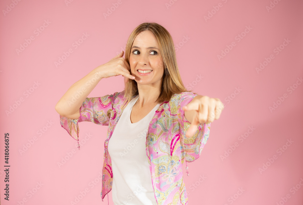 Young woman over isolated pink background making phone gesture. Call me back sign Young woman over isolated pink background making phone gesture. Call me back sign