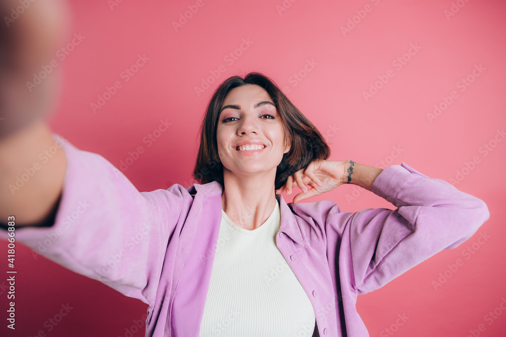 Young cute women casual wear on pink background smiling and looking at camera while taking selfie photo Young cute women casual wear on pink background smiling and looking at camera while taking selfie photo