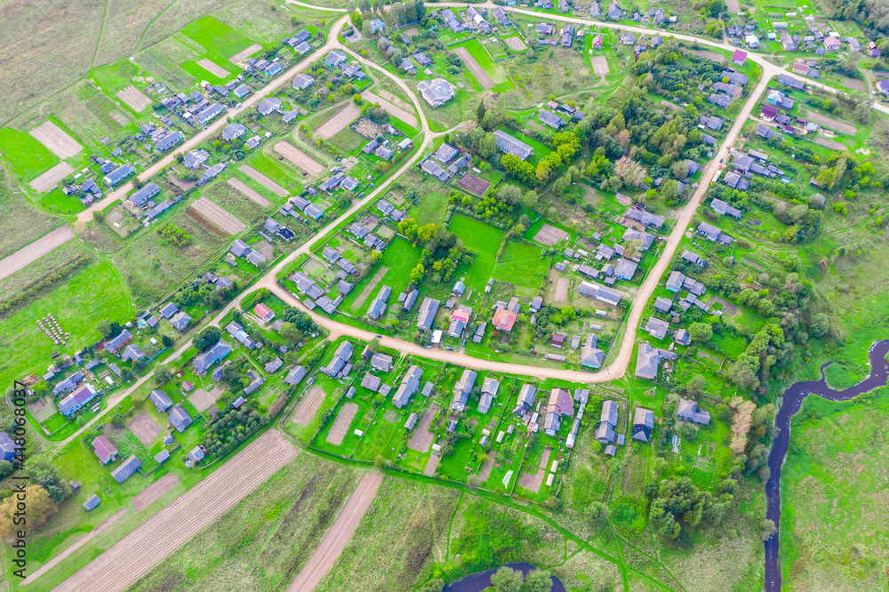 Beautiful small green village from above, dirt roads, streets, vegetable gardens,plowed fields, meadows, houses. Aerial top view.