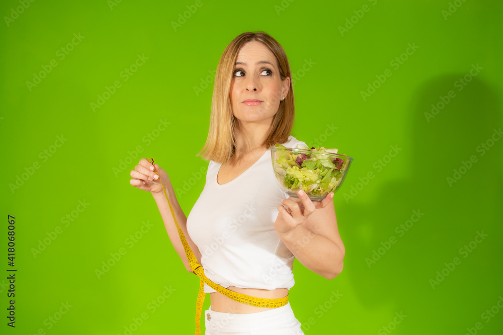 Woman diet concept portrait. Young woman hold green salad and measure tape. Isolated portrait. Woman diet concept portrait. Young woman hold green salad and measure tape. Isolated portrait.