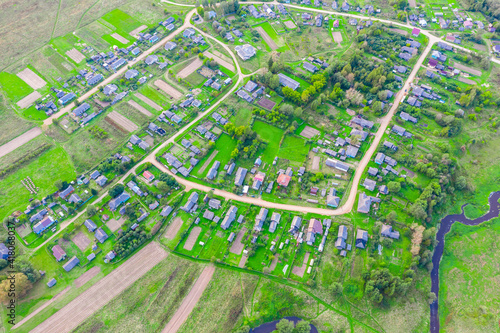 Beautiful small green village from above, dirt roads, streets, vegetable gardens,plowed fields, meadows, houses. Aerial top view.