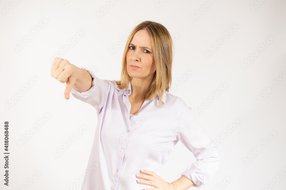 Portrait of displeased woman who is showing thumb down over white background. Portrait of displeased woman who is showing thumb down over white background.