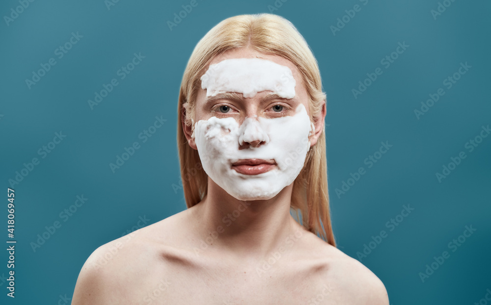 Groomed young blond man washing his face with foam Groomed young blond man washing his face with foam