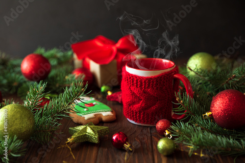 Hot Christmas tea with steam and gingerbread cookie on wooden table. New Year and Christmas celebration concept.