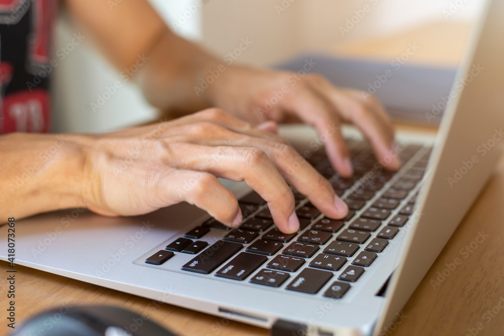 Close up image of young businessman using laptop and working online at home. He is typing on computer sitting at wooden table. Work from home concept. Close up image of young businessman using laptop and working online at home. He is typing on computer sitting at wooden table. Work from home concept.