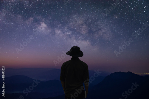 Silhouette of young traveler and backpacker standing on top of the mountain and watched the star and milky way over the sky alone.