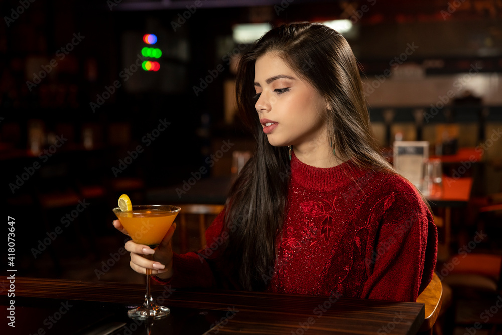 Portrait of a pretty female drinking juice while sitting in a restaurant.