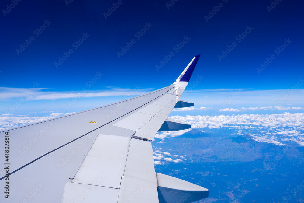 Obraz premium Photo of airplane wing with clouds background, horizon line and clear blue sky