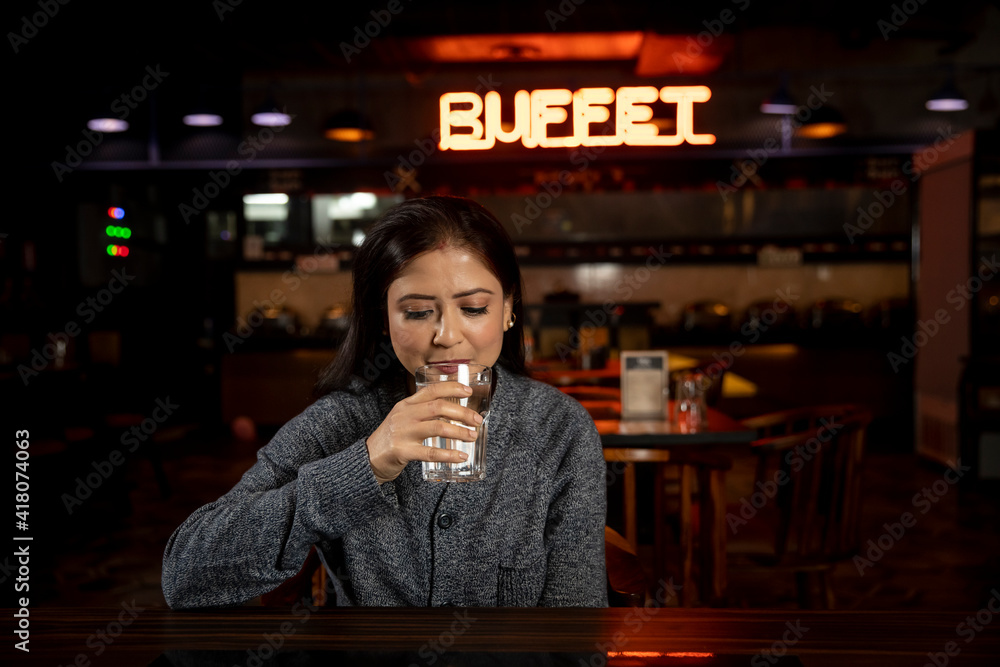 Portrait of a woman drinking water in a restaurant.