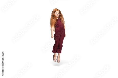 Jumping, flying. Happy, smiley little caucasian girl isolated on white studio background with copyspace for ad. Looks happy, cheerful. Childhood, education, human emotions, facial expression concept.