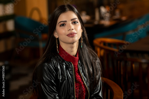 Portrait of a pretty young woman sitting in a restaurant. © Bhaven