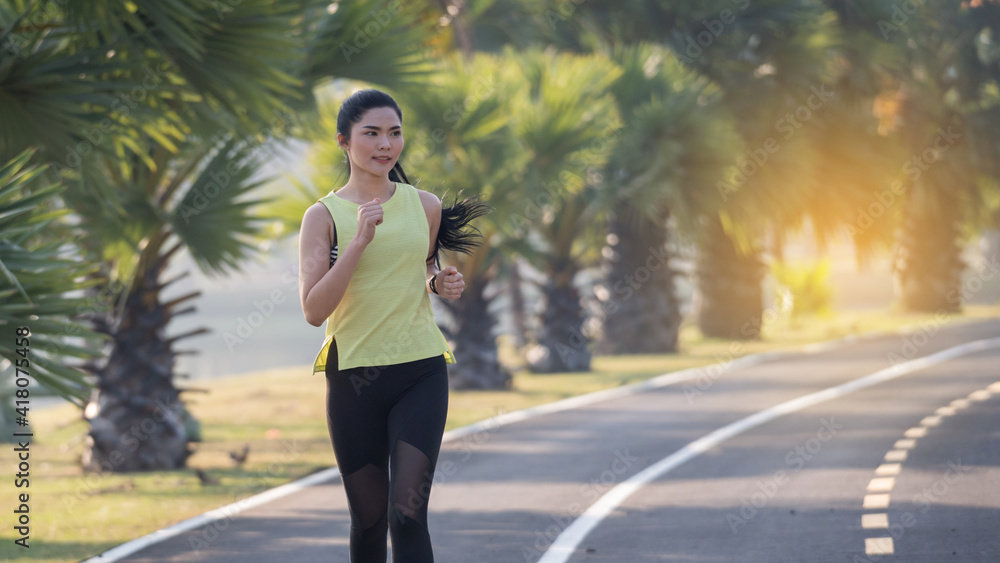A young Asian woman athlete runner jogging in city stadium in the sunny morning to keep fitness and healthy lifestyle. Active healthy runner jogging outdoor. Sports and recreation A young Asian woman athlete runner jogging in city stadium in the sunny morning to keep fitness and healthy lifestyle. Active healthy runner jogging outdoor. Sports and recreation