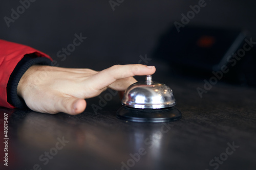 Man's hand on the bell, calling the manager in the hotel lobby