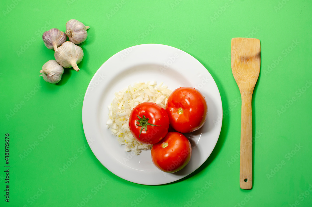 red tomatoes with sliced onions lie on a white plate green background red tomatoes with sliced onions lie on a white plate green background