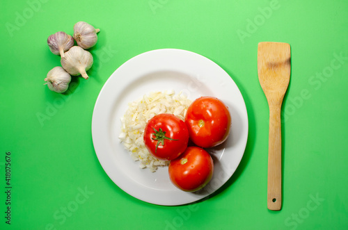 red tomatoes with sliced onions lie on a white plate green background