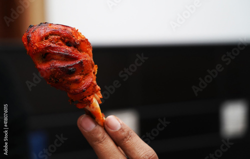 close up image of a piece of fried and roasted chicken tandoori leg piece.Its a spicy north indian starter dish