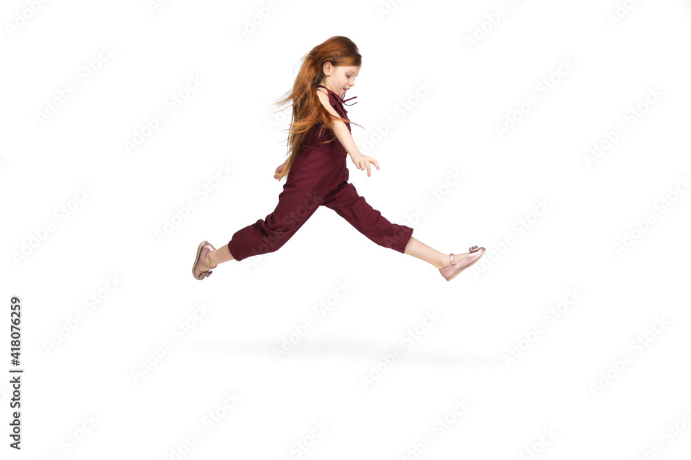Jumping, flying. Happy, smiley little caucasian girl isolated on white studio background with copyspace for ad. Looks happy, cheerful. Childhood, education, human emotions, facial expression concept.