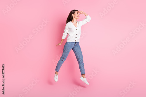 Full body photo of happy cheerful positive young woman jump up hand head look empty space isolated on pink color background