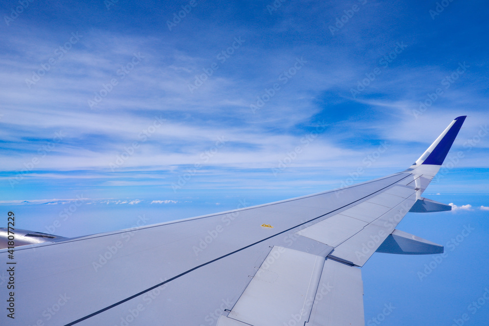 Photo of airplane wing with clouds background, horizon line and clear blue sky