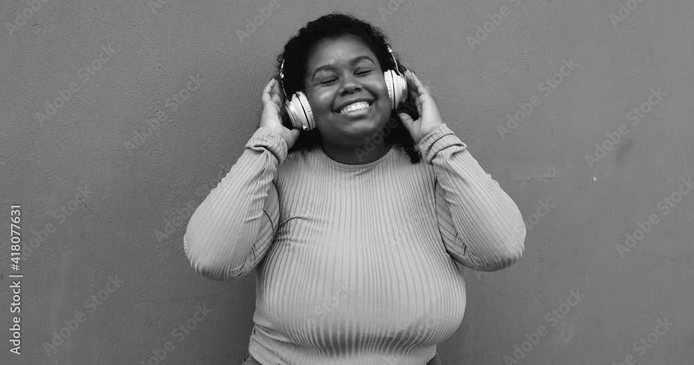 Young curvy latin woman dancing to music playlist while wearing headphones Young curvy latin woman dancing to music playlist while wearing headphones