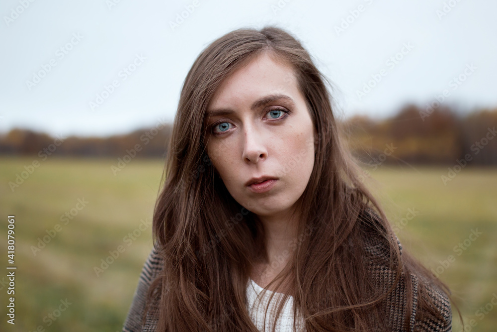 Sad girl with blue eyes. Portrait of a girl in brown tones. Walk through the woods. Autumn colors. Girl with long hair